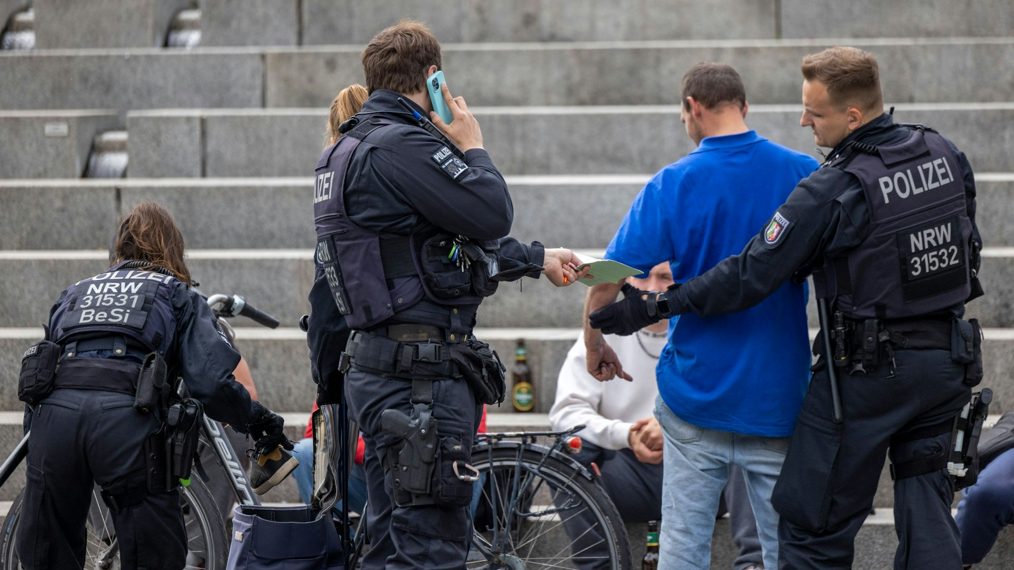 Beamte der Polizei kontrollieren Personen auf dem Wiener Platz. Am Wiener Platz in Köln-Mülheim gilt seit Mittwoch die erste permanente Waffenverbotszone in Nordrhein-Westfalen. Sie beziehe sich auf Messer, Schlagstöcke, Pfefferspray und andere Waffen.