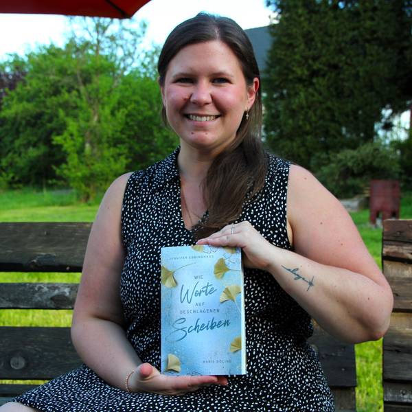 Eine junge Frau hält ein Buch in die Kamera.