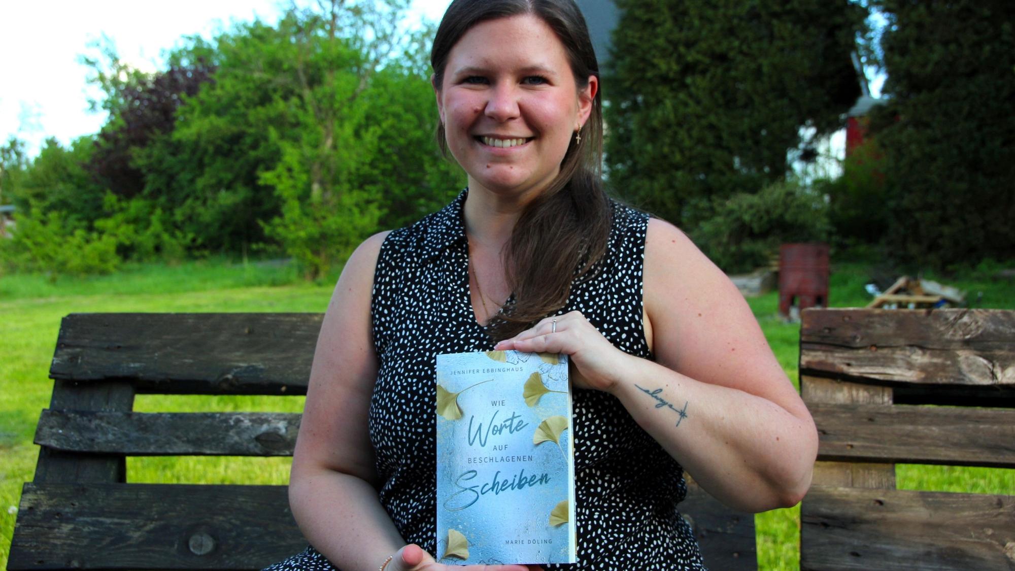 Eine junge Frau hält ein Buch in die Kamera.