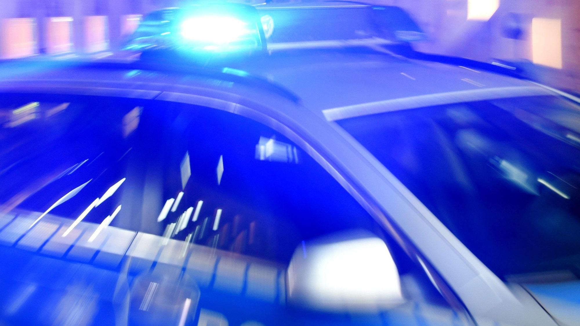 Ein Streifenwagen der Polizei steht mit eingeschaltetem Blaulicht auf der Straße.