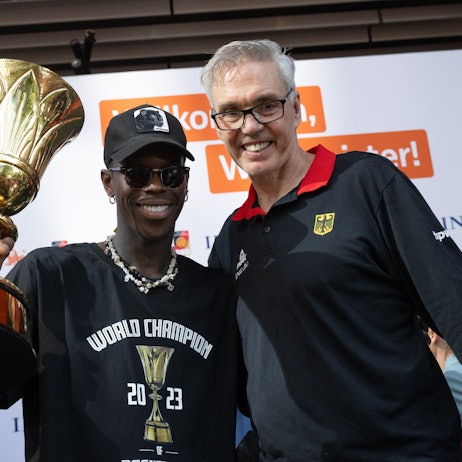 Dennis Schröder (l), Kapitän der Basketball-Nationalmannschaft, und Bundestrainer Gordon Herbert (r) jubeln beim Empfang des Teams in Frankfurt mit dem Pokal. Herbert verlässt die Nationalmannschaft nach Olympia.