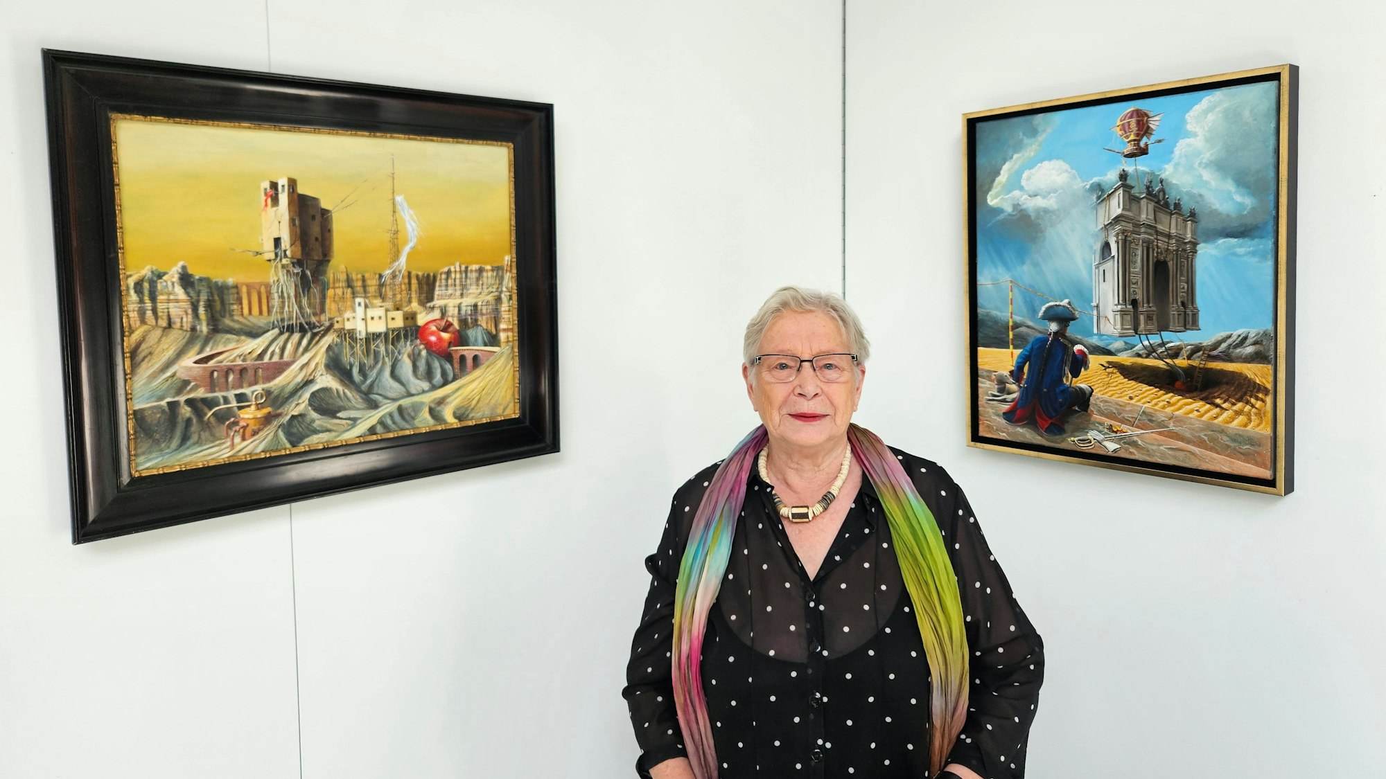 Kuratorin Eva-Maria Hermanns steht zwischen zwei Bildern der Ausstellung.