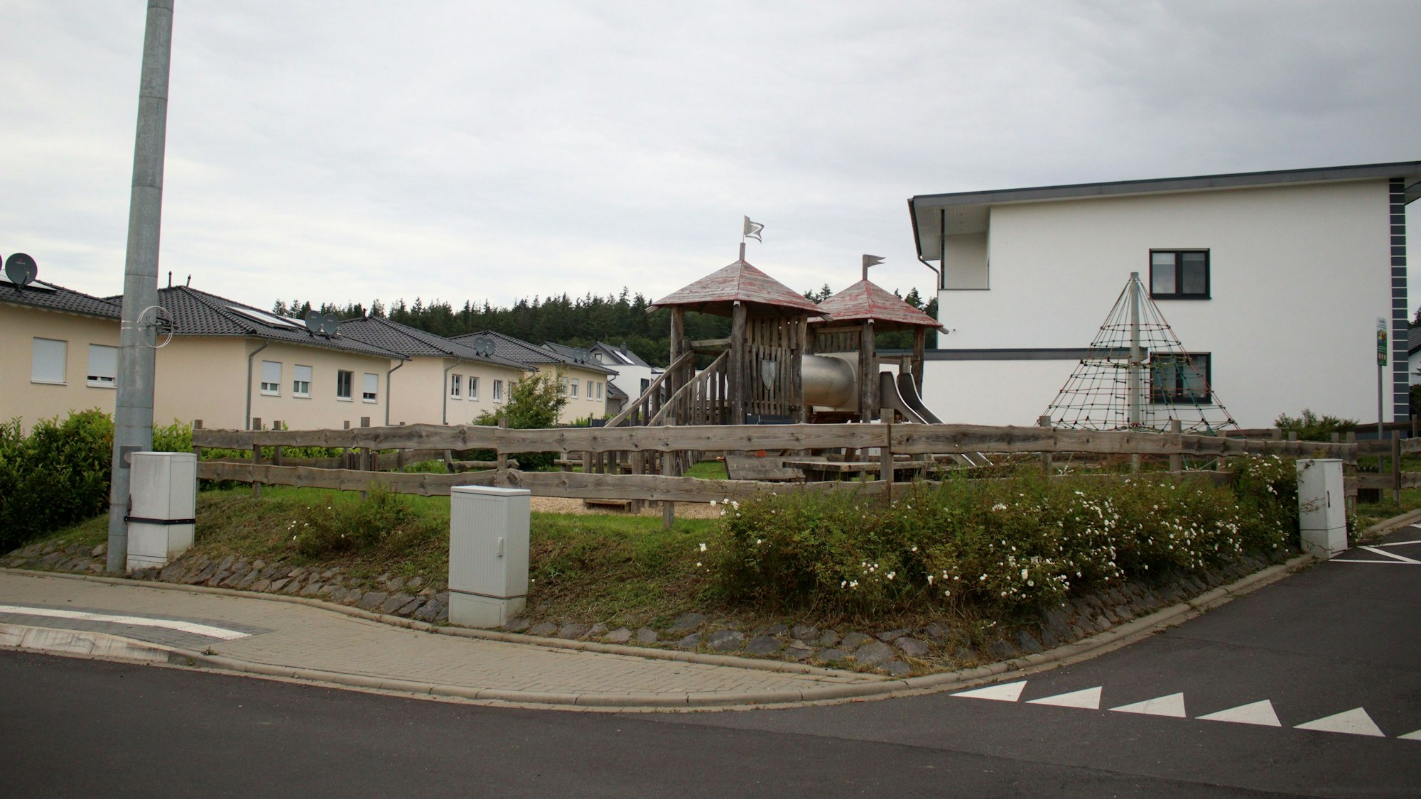 Das Bild zeigt den Spielplatz an der Stotzheimer Straße in Kirspenich von der Straße aus. Im Hintergrund die umliegenden Wohngebäude.