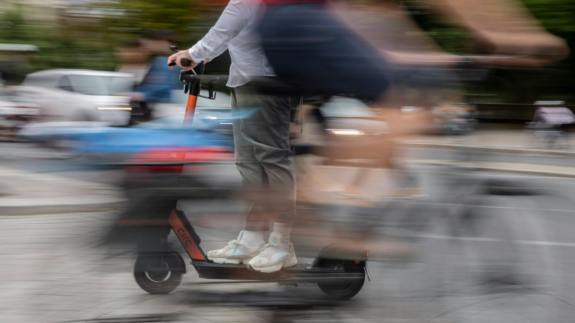 Ein E-Scooter-Fahrer kreuzt den Weg vor einem Fahrradfahrer.