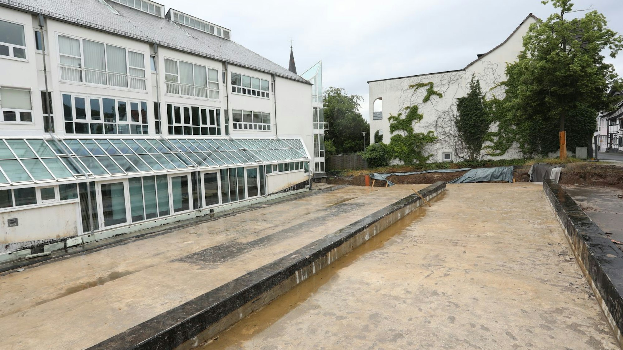 Eine rötliche Betonfläche auf der Rückseite eines Gebäudes, das mit vielen Fenstern versehen wurde.