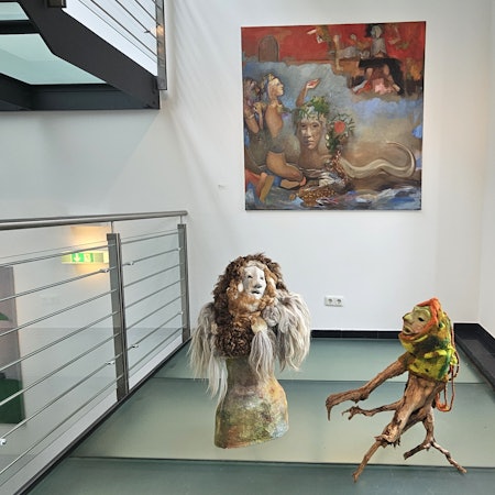 Vor einem Bild mit Lebewesen aus fremden Welten stehen zwei Figuren, die an Geister erinnern.