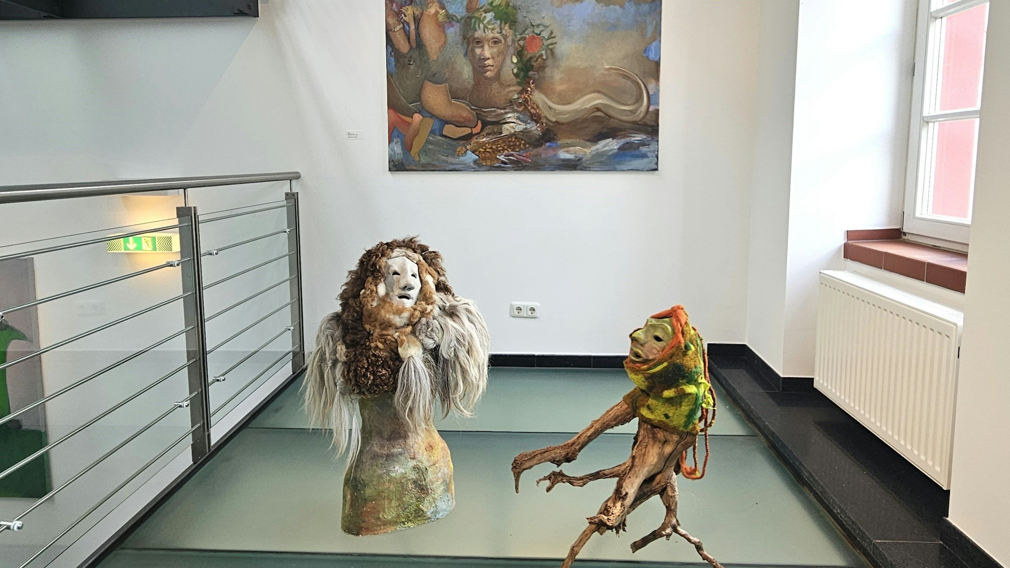 Vor einem Bild mit Lebewesen aus fremden Welten stehen zwei Figuren, die an Geister erinnern.