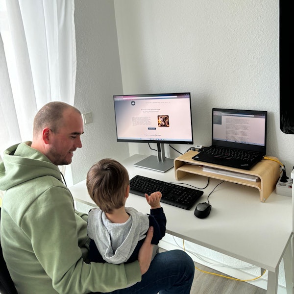 Vater und Sohn sitzen vor dem Computer, auf dem eine Gute-Nacht-Geschichte zu lesen ist.