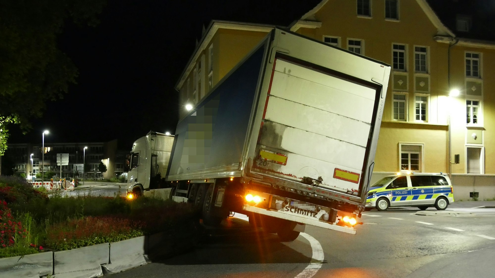 Der Auflieger eines Lkw hängt schief von der Erhöhung eines Kreisels.