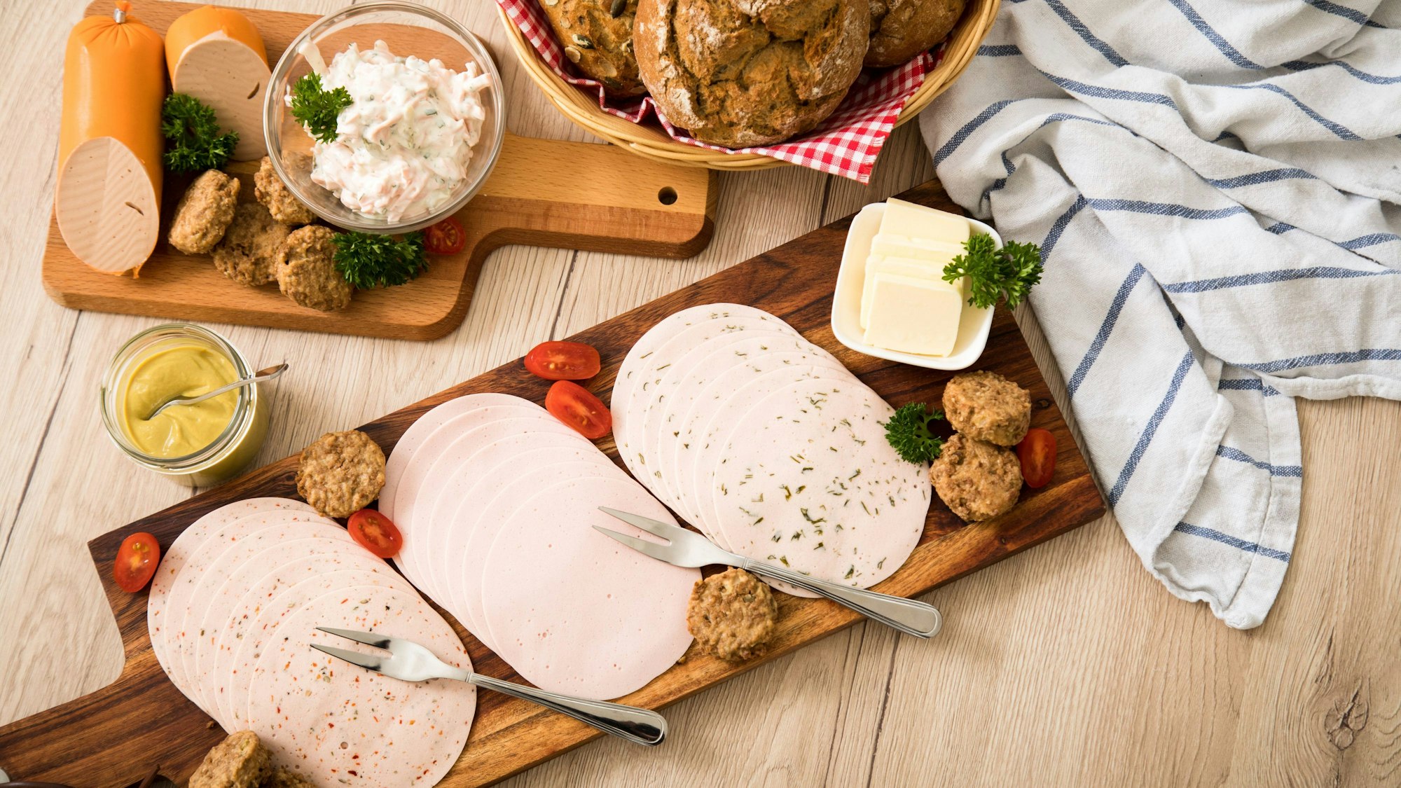 Auf einem Tisch sind vegetarische Salate und vegetarischer Wurstaufschnitt angerichtet.