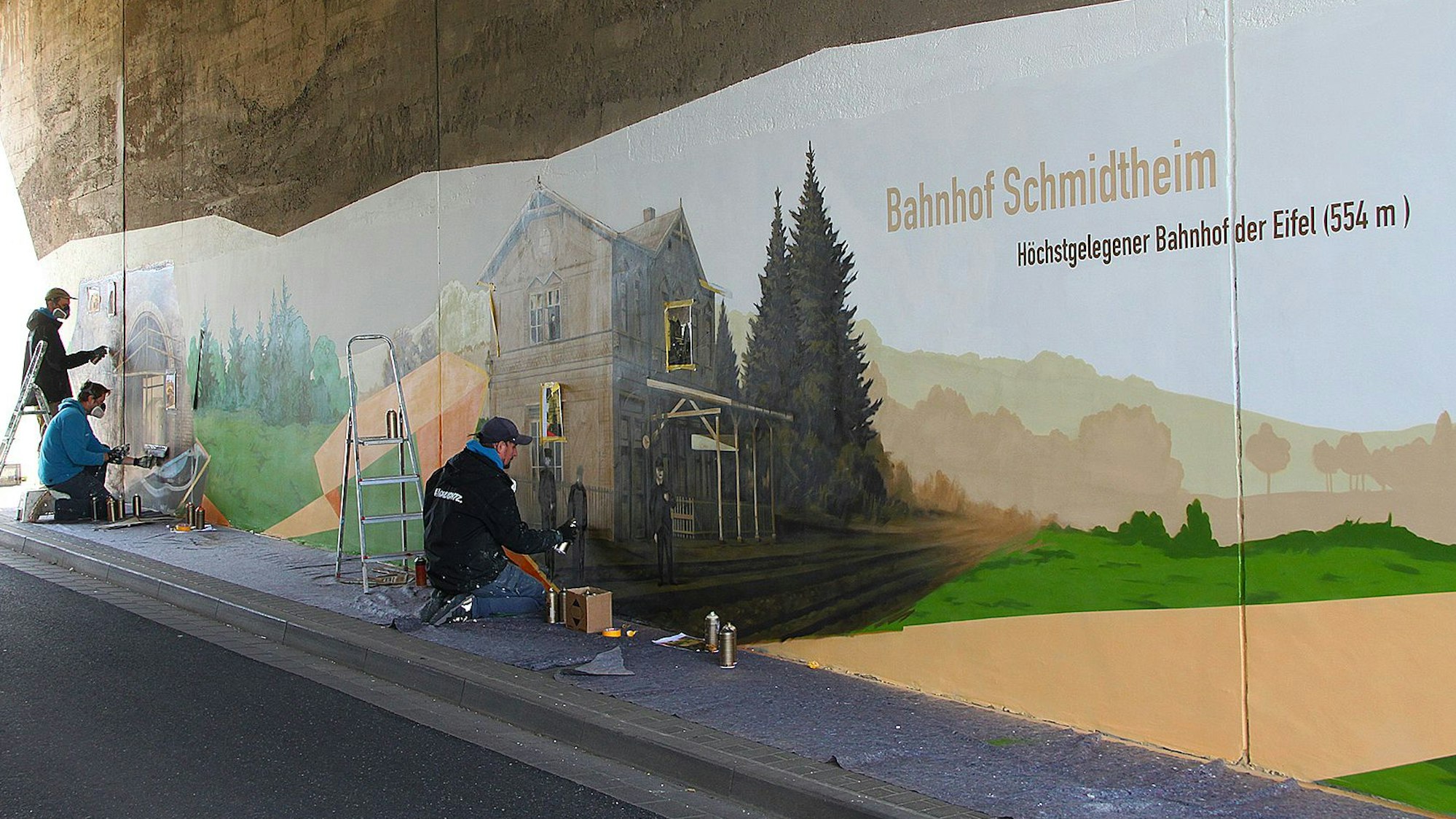 Zu sehen sind drei Künstler bei der Arbeit in der Unterführung.