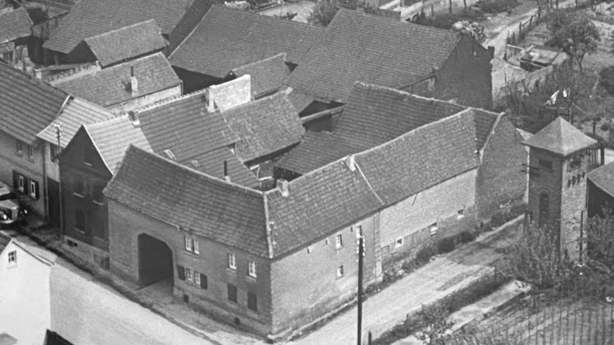 Der Lastwagen am Bildrand parkt vor der damaligen Unternehmenszentrale, im Mittelpunkt sind der landwirtschaftliche Betrieb und die Wohnung von Hündgens 1957 zu sehen.