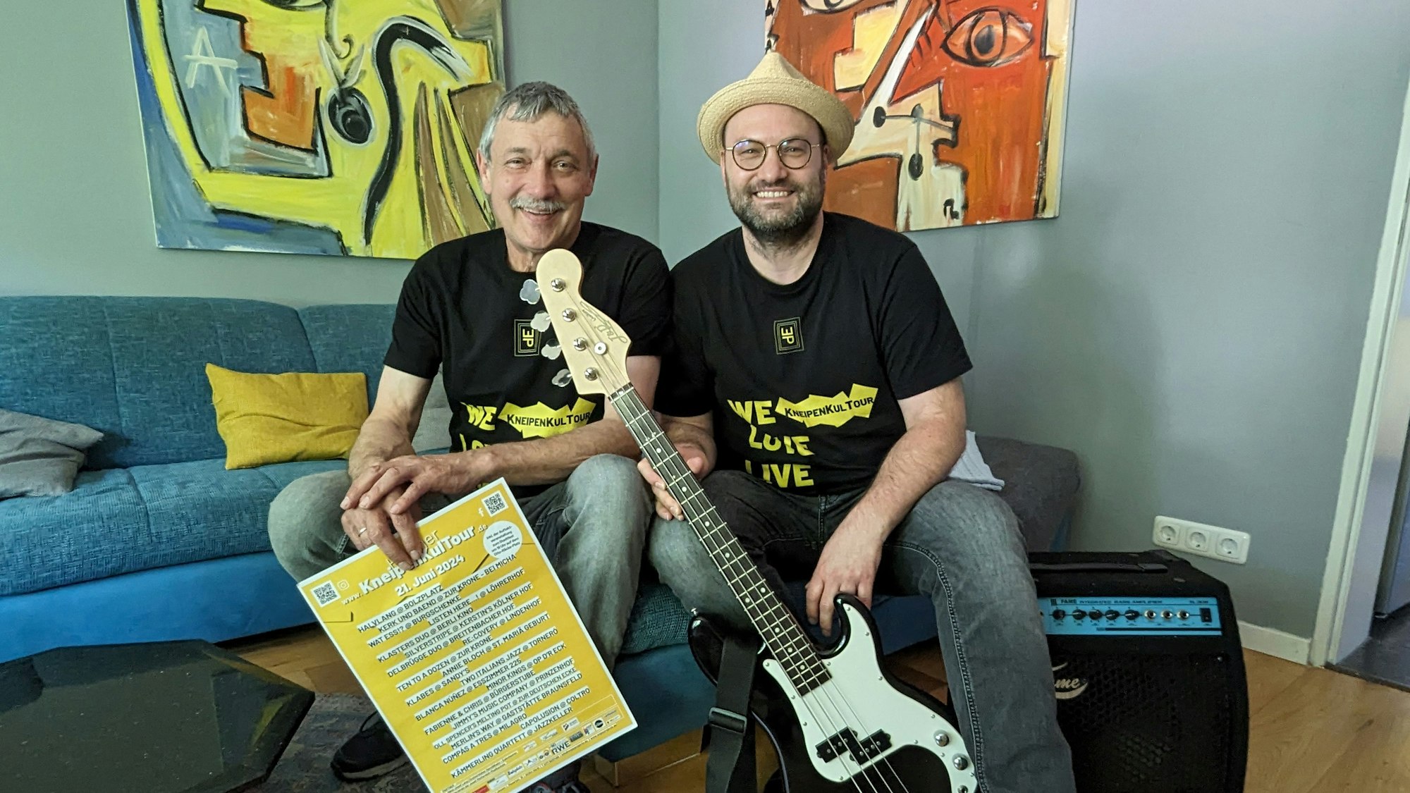 Das Foto zeigt die beiden Organisatoren mit Plakat, Bassgitarre und Verstärker.