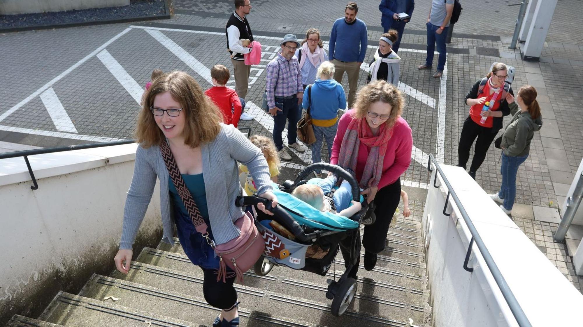 Zwei Frauen tragen einen Kinderwagen die Freitreppe zum Ratssaal im Bad Honnefer Rathaus hinauf.