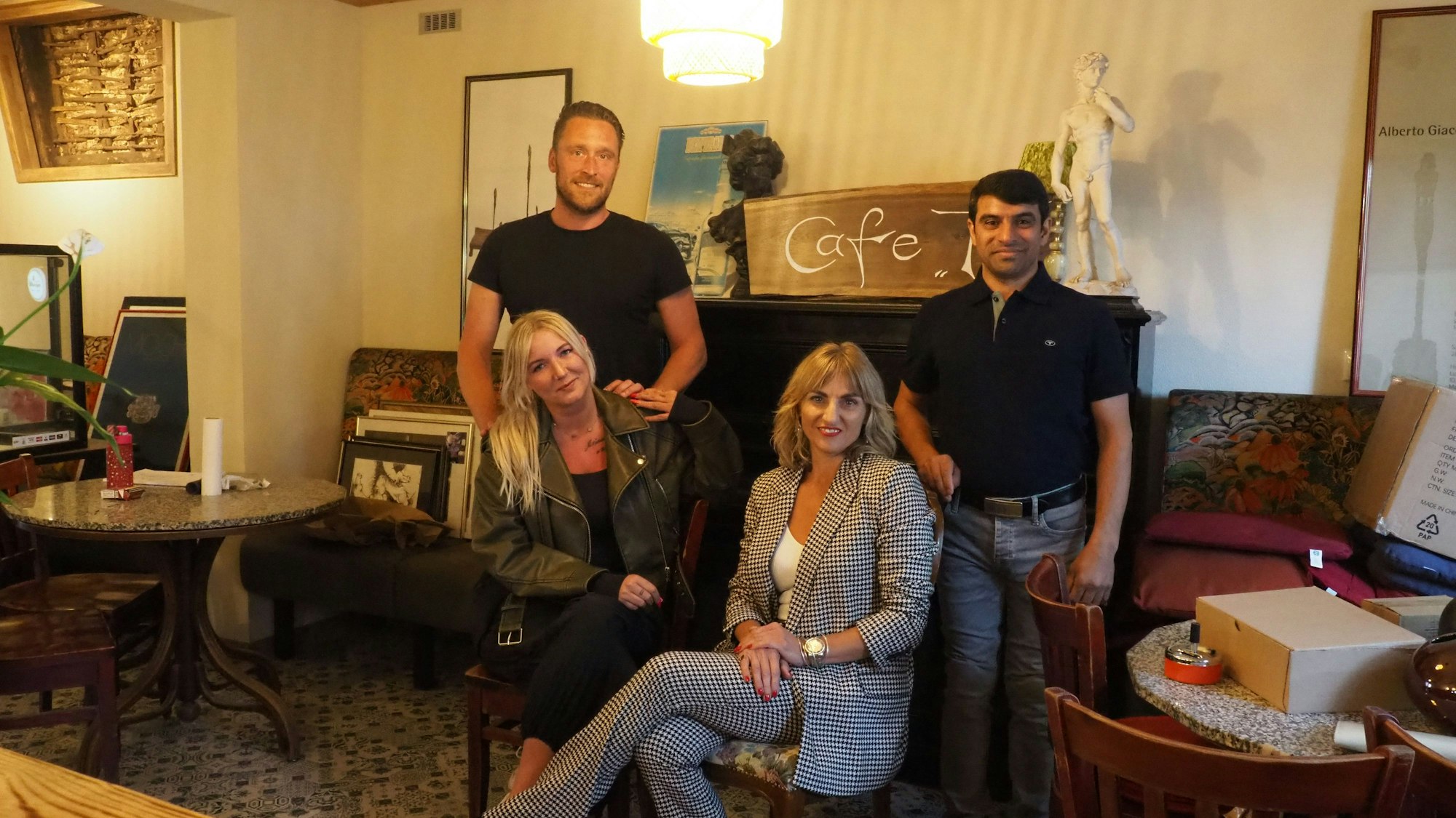 Markus Prusko und Sadeq Ali Hosseine stehen hinter Angela Dar und Jeanette Heinzen, die es sich auf Stühlen bequem gemacht haben.