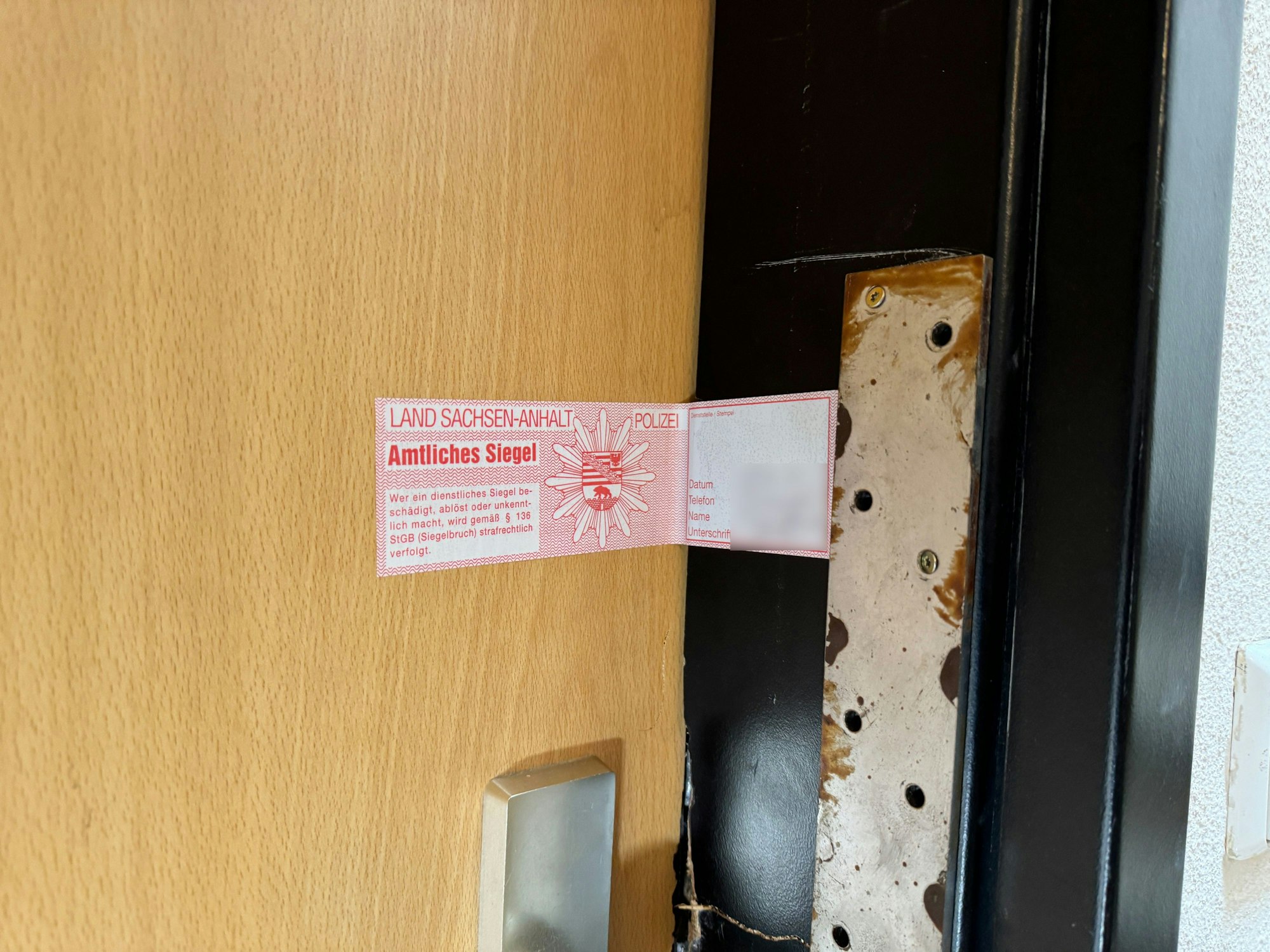 15.06.2024, Sachsen-Anhalt, Wolmirstedt: Ein Polizeisiegel ist an einer Tür angebracht. Polizisten haben bei einem Einsatz in Wolmirstedt nördlich von Magdeburg am Freitagabend einen Mann erschossen. Dieser hat vorher die Beamten angegriffen, wie eine Polizeisprecherin am Samstagmorgen in Stendal sagte. Er starb den Angaben zufolge noch vor Ort. Foto: Thomas Schulz/dpa - ACHTUNG: Siegel wurde gepixelt +++ dpa-Bildfunk +++