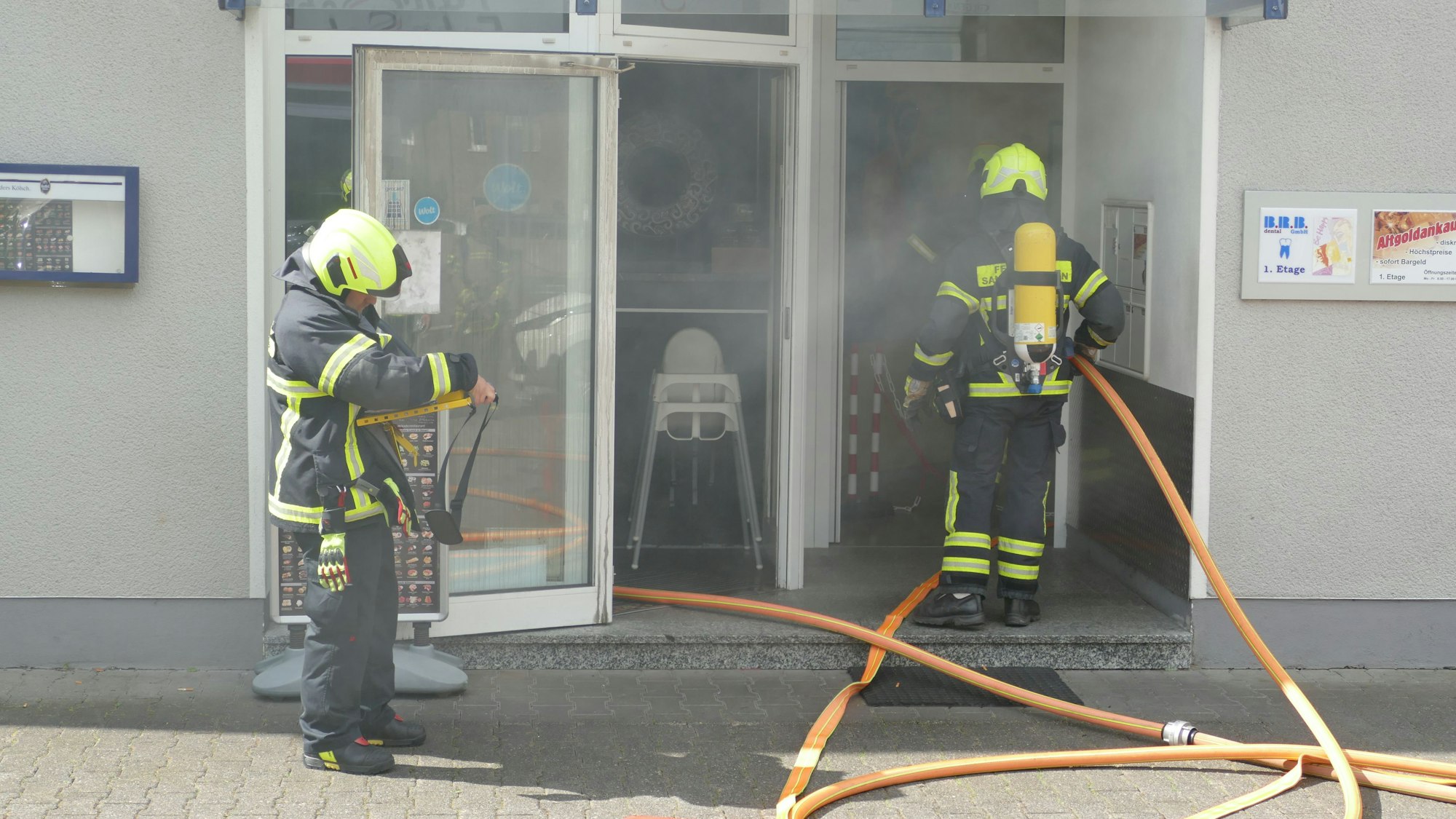 Rauch dringt aus dem Restauranteingang, in dem die Feuerwehrleute stehen.