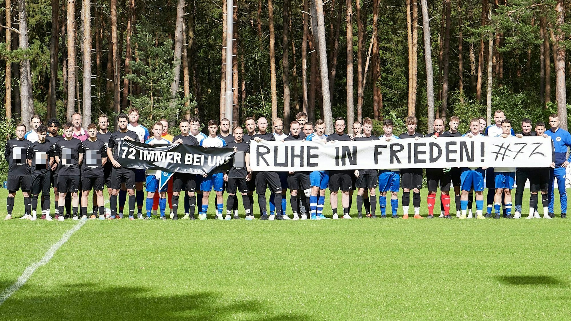 Die beiden Mannschaften haben sich nebeneinander auf dem Spielfeld aufgestellt und halten zwei Banner hoch. Auf dem einen steht zu lesen: 72 immer bei uns". Auf dem anderen: Ruhr in Frieden Hashtag 72.