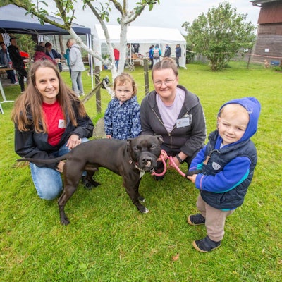 Zwei Frauen und zwei Kinder hocken neben einem Hund.