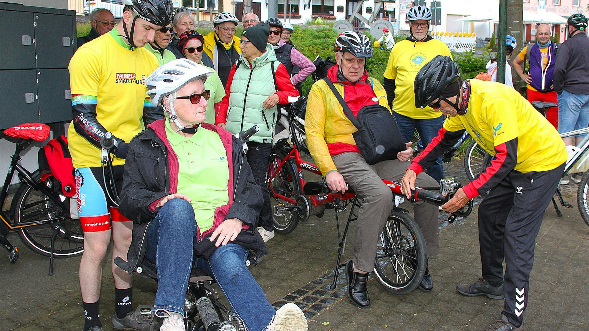 Während die beiden blinden Eheleute vorne auf den E-Tandems Platz genommen haben, bereiten die Piloten die Räder für die Fahrt vor.