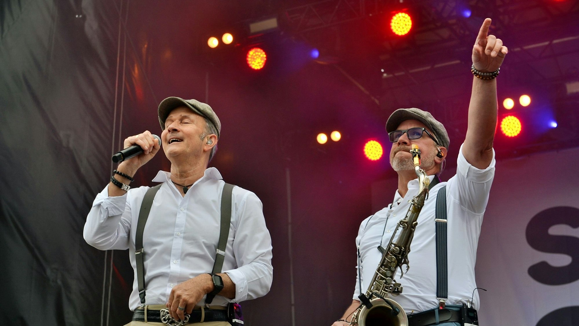 Zwei Musiker der Gruppe Klüngelköpp, einer mit Mikrofon, der andere mit Saxofon, bei ihrem Auftritt in Zülpich.