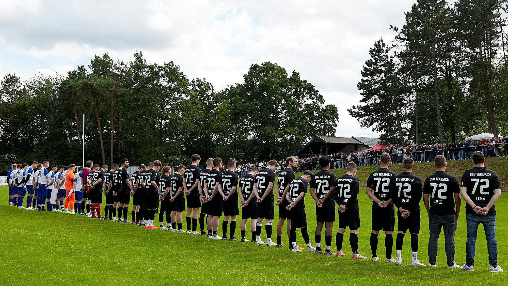 Die Spieler bilden eine Reihe vor dem Publikum. Alle Spieler aus Golbach tragen schwarze Trikots mit der Rückennummer 72.