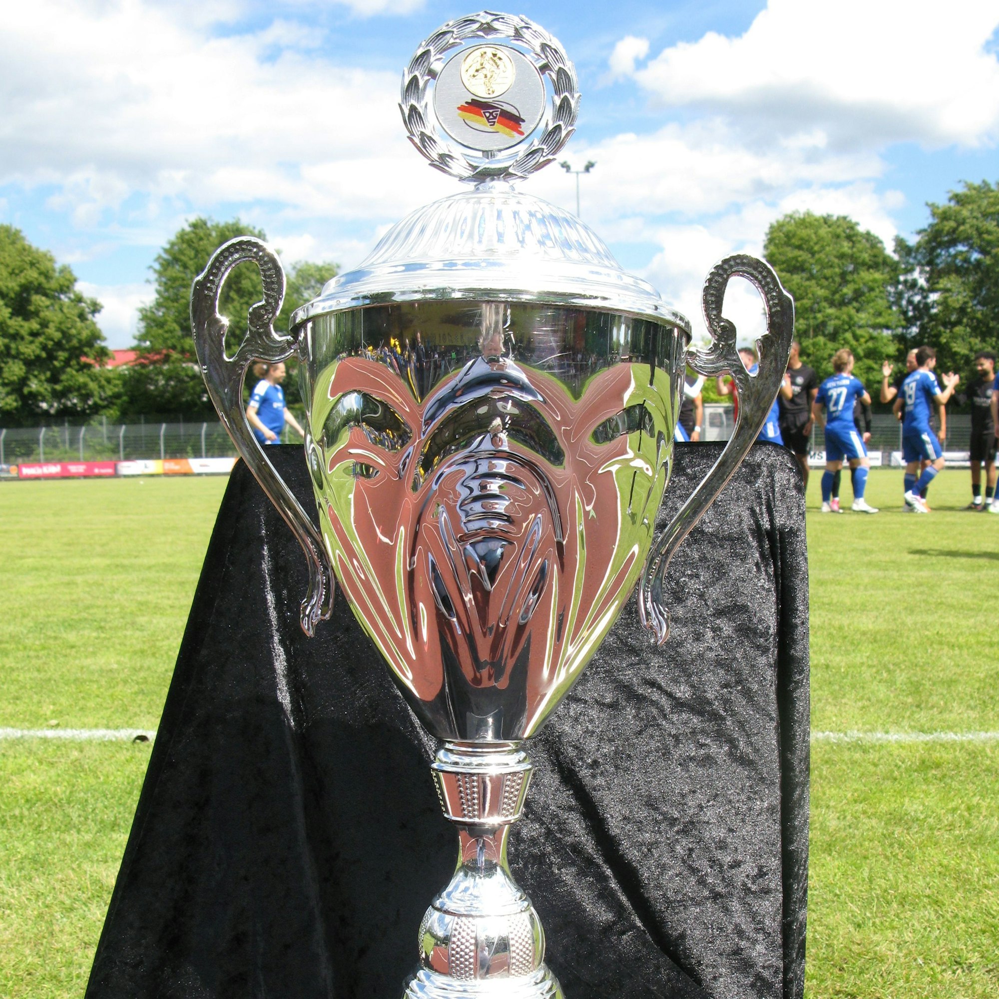 Der große, silberne Pokal für den Deutschen Meister im Gehörlosen-Fußball am Spielfeldrand.