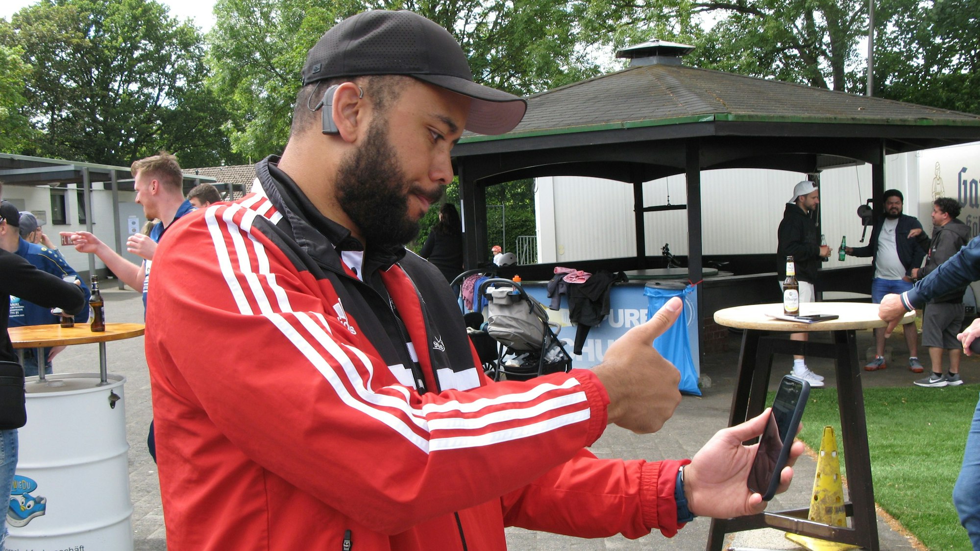 Ein gehörloser Funktionär des Kölner Gehörlosen-Sportvereins macht ein Handzeichen beim Telefonieren mit einem Smartphone.