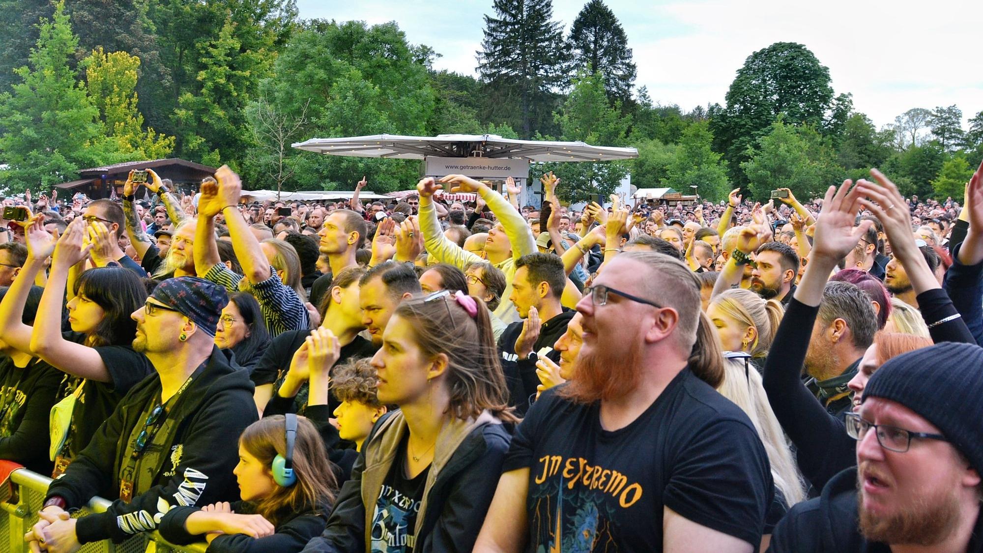 Das Bild zeigt einen Teil der Zuschauer, die stehend das Konzert verfolgen. Einige tragen T-Shirts mit dem Namen der Band.