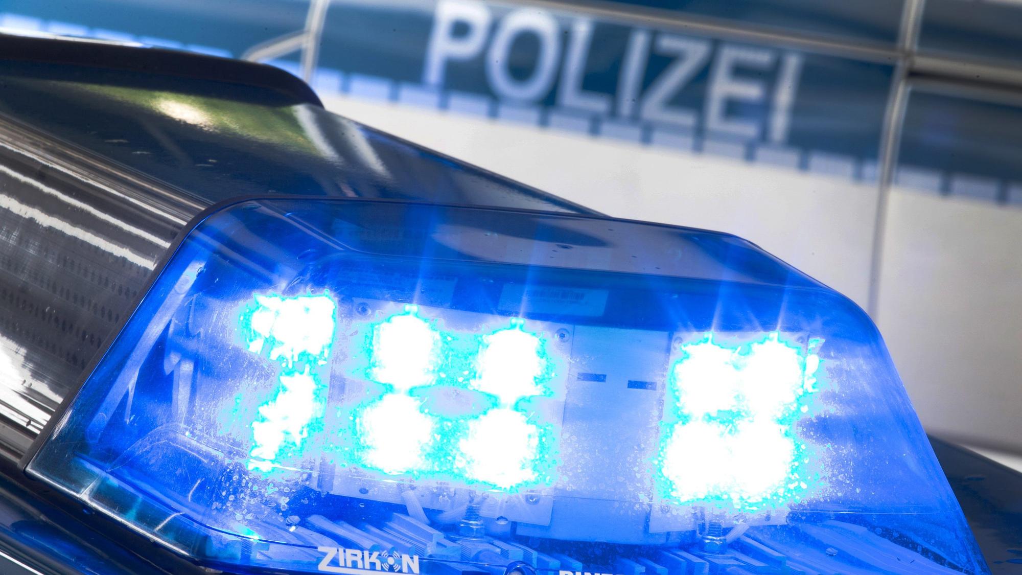 Ein Blaulicht leuchtet auf dem Dach eines Polizeiwagens. Im Hintergrund steht ein weiterer Streifenwagen.
