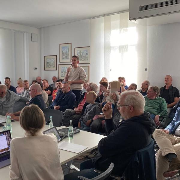 Im Publikum steht ein Anwohner mit Mikrofon. Die Ratsmitglieder hören zu.