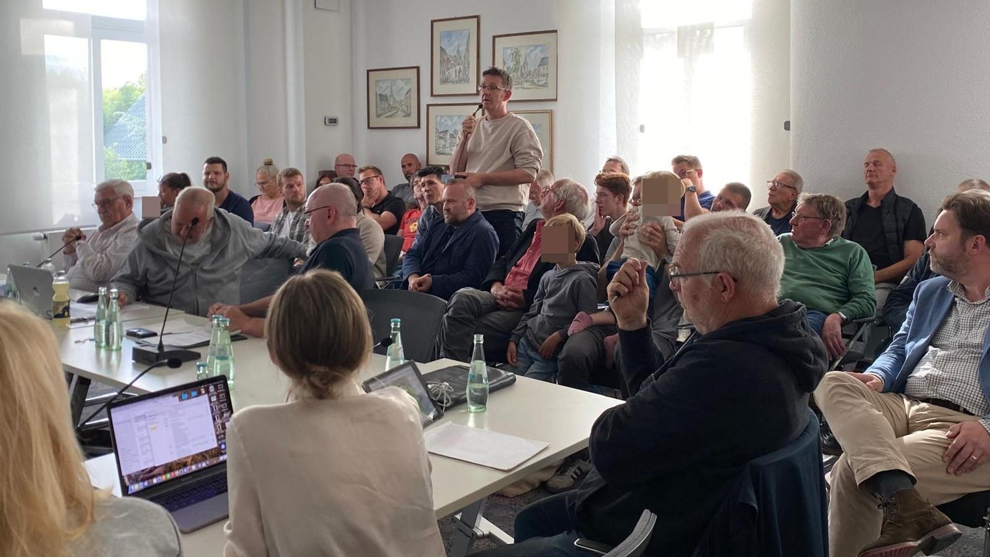 Im Publikum steht ein Anwohner mit Mikrofon. Die Ratsmitglieder hören zu.