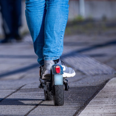 Das Bild zeigt einen E-Scooter-Fahrer von der Rückseite.
