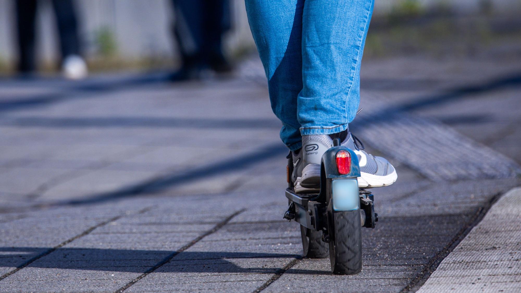 Ausschnitt eines Fahrers auf einem E-Scooter.