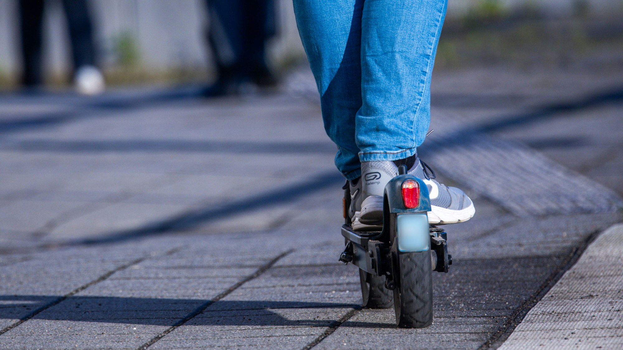 Ausschnitt eines Fahrers auf einem E-Scooter.