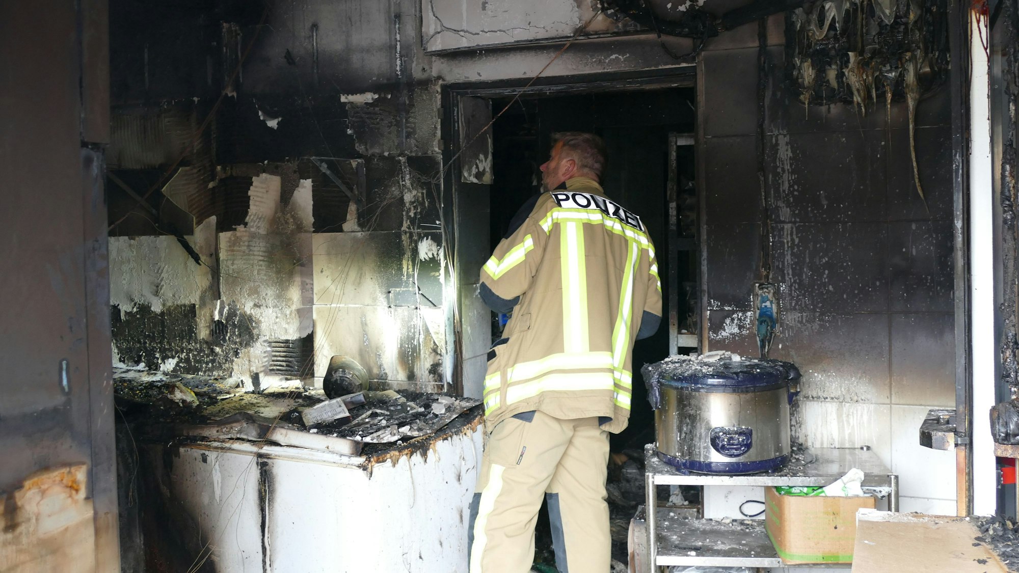 Ein Brandermittler der Polizei steht inmitten der ausgebrannten Küche.