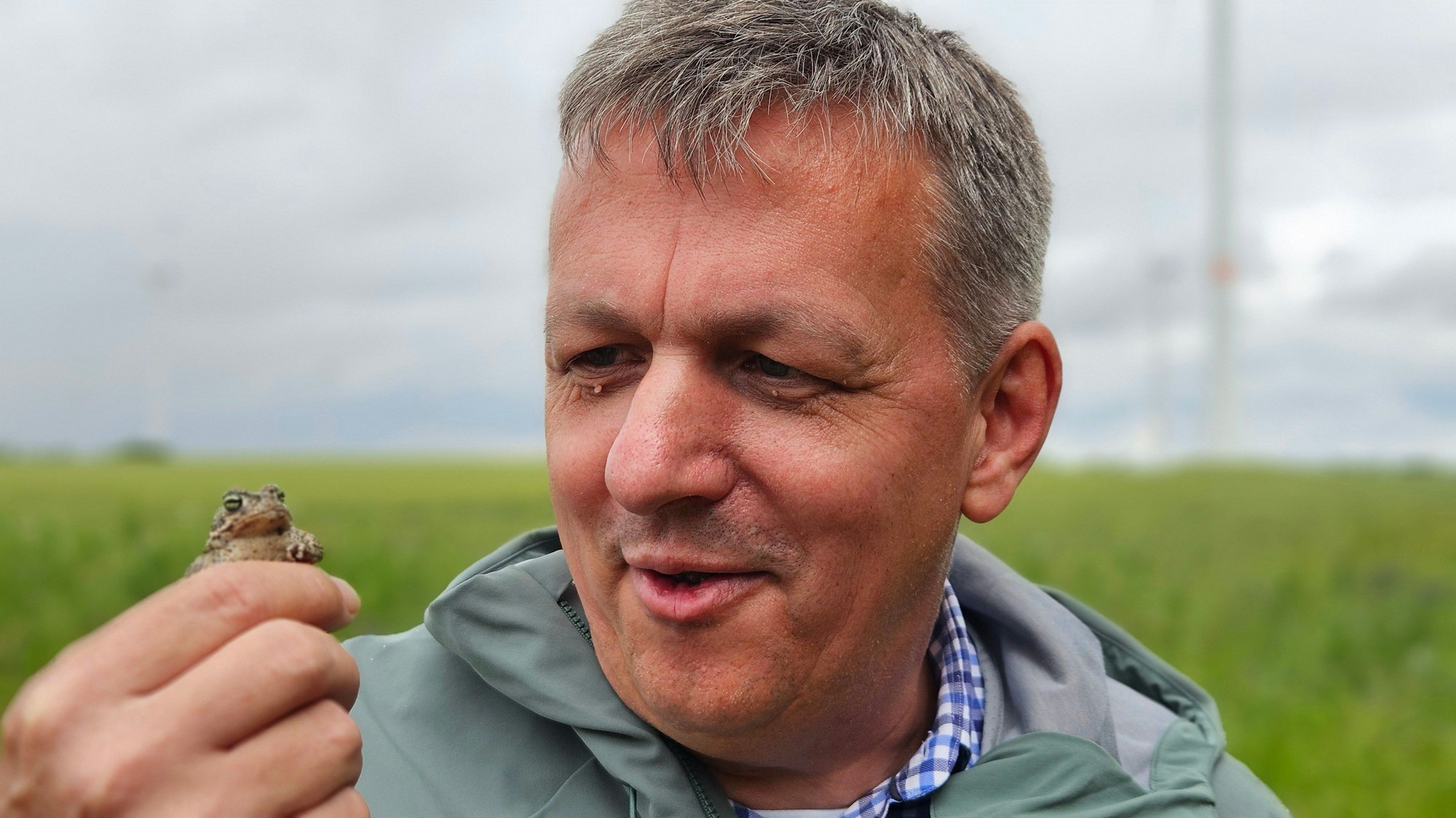 Ein Mann hält eine kleine Kröte in der Hand.