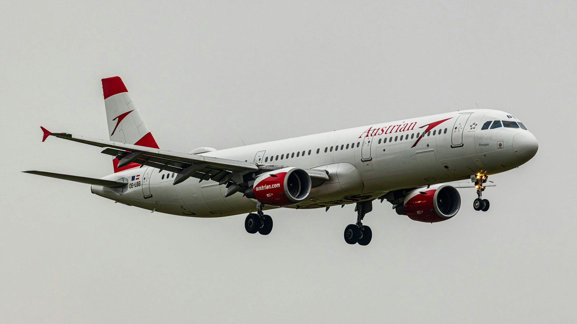 Ein rot-weiß-lackierter Airbus A320 der österreichischen Fluggesellschaft Austrian Airlines im Landeanflug auf einen Flughafen. (Symbolbild)
