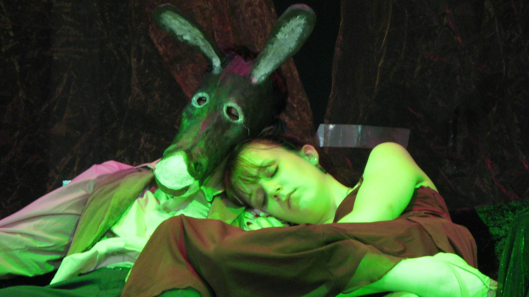 Ein schlafendes Paar, bestehend aus der Elfenkönigin Titania in einem roten Kleid und der Handwerker Zettel mit einem Eselskopf.