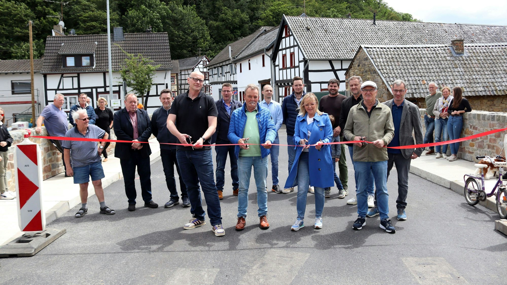 Die Bürgermeisterin und drei Politiker mit Scheren in den Händen durchtrennen auf einer Brücke ein rotes Band. Im Hintergrund stehen Menschen, die zuschauen.