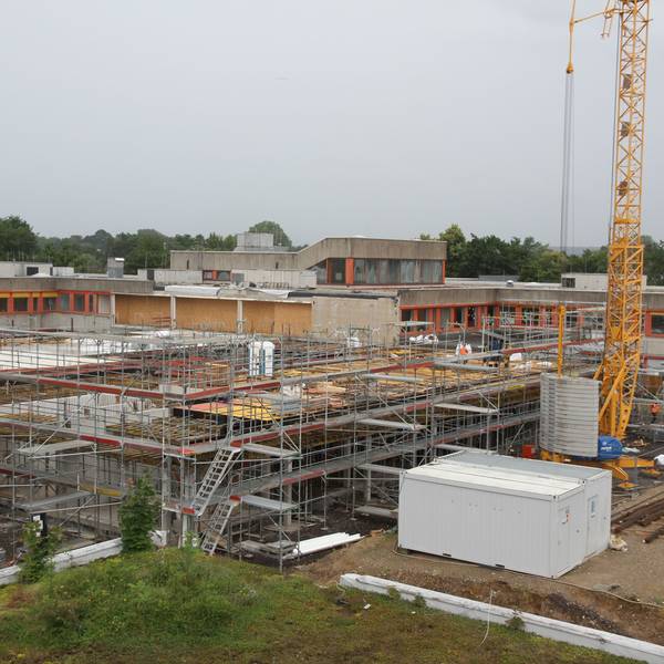 Blick auf eine Großbaustelle, im Hintergrund ein Schulzentrum
