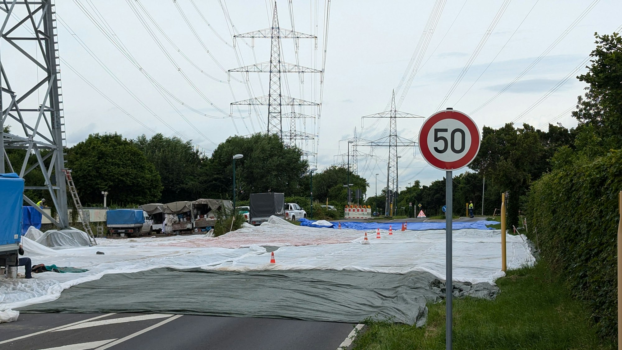 Das Foto zeigt eine abgedeckte Fahrbahn an einem Hochspannungsmast.