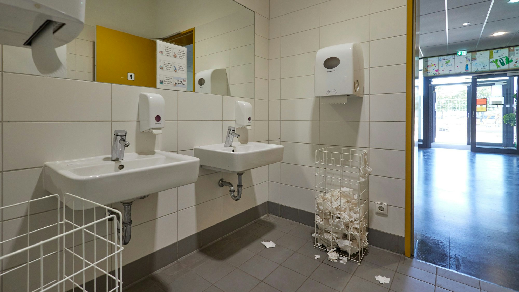 Papier liegt im Waschraum einer Schultoilette herum.