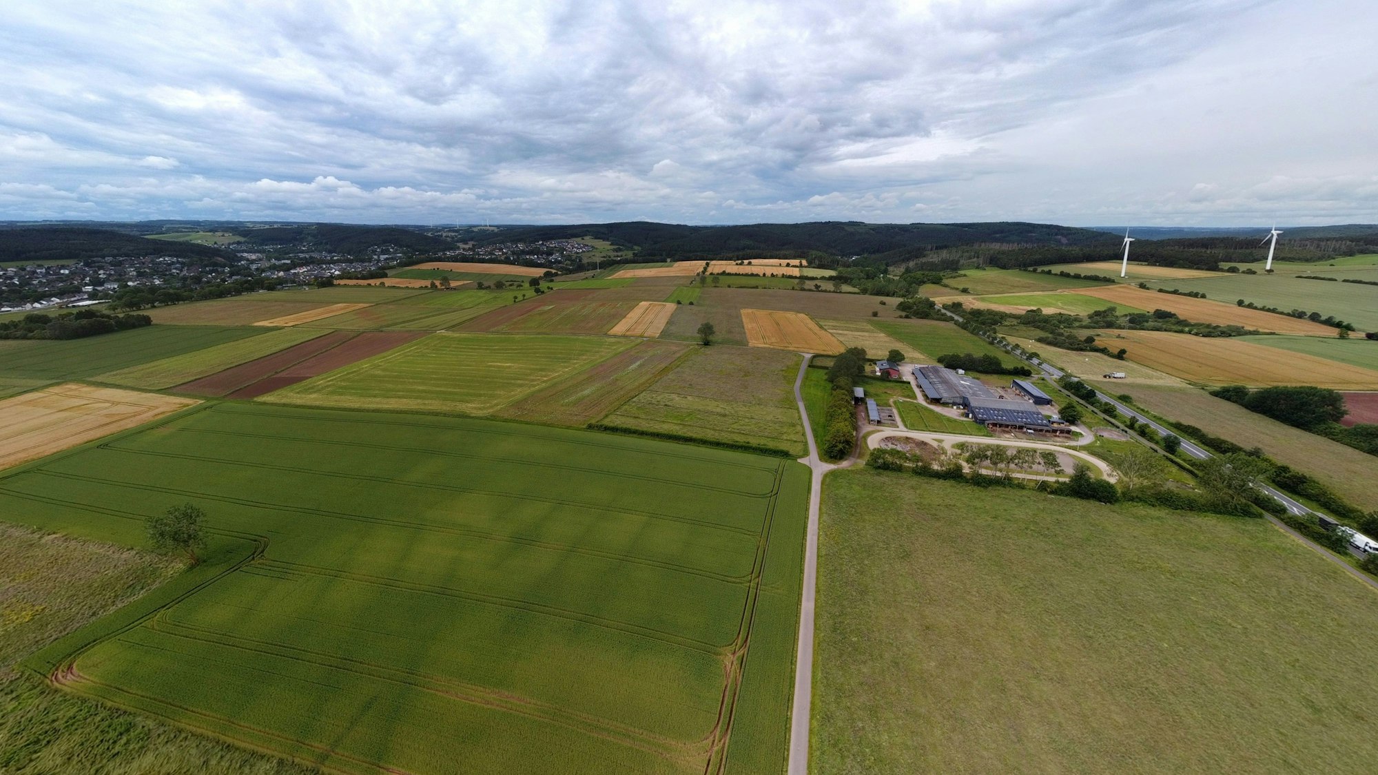 Luftbild mit Äckern, Wiesen und einem Reiterhof.