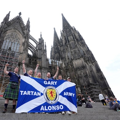 Mehrere schottische Anhänger stehen vor dem Kölner Dom und halten eine Flagge der „Tartan Army“ vor sich. Ein schottischer Fan ist kurz vor dem zweiten Gruppenspiel der Schotten gegen die Schweiz plötzlich gestorben. (Symbolbild)
