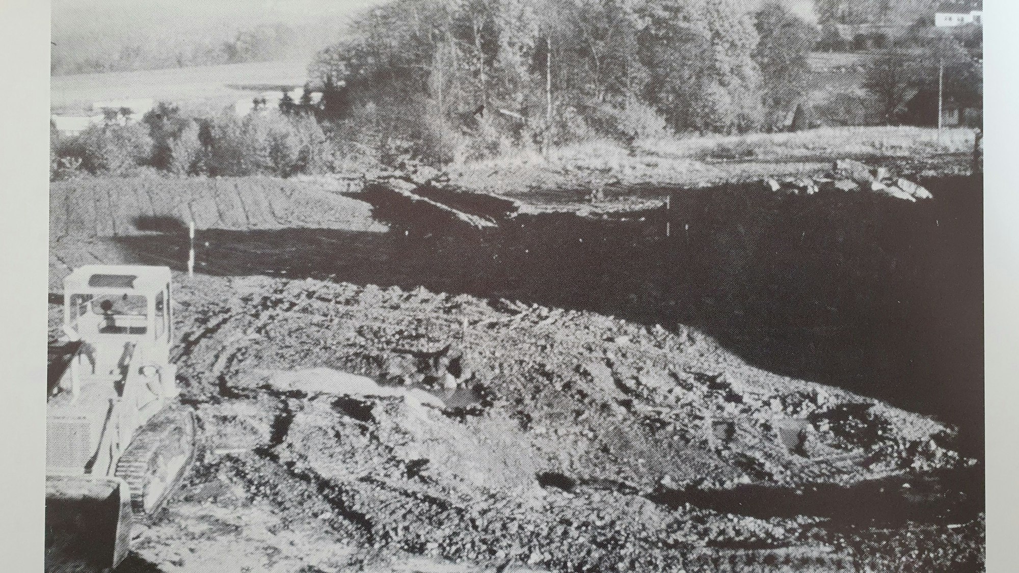 Ein Bagger im Vordergrund. Schlammberge im Hintergrund.