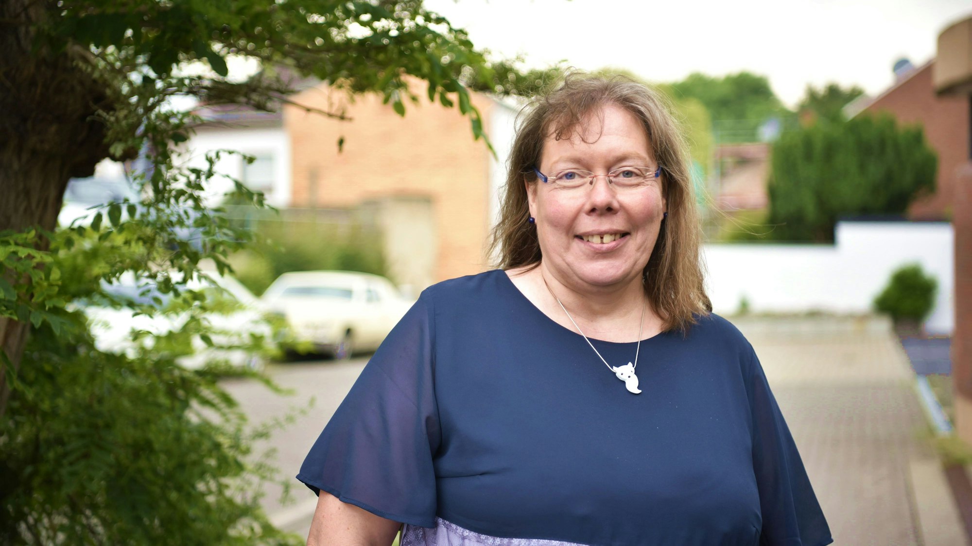 Kerstin Roscher steht auf einem Bürgersteig in Zülpich, links von ihr ist ein Baum zu erkennen.
