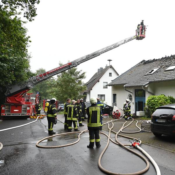Die Feuerwehr hat über dem Haus eine Drehleiter ausgefahren, Einsatzkräfte stehen auf der Straße.
