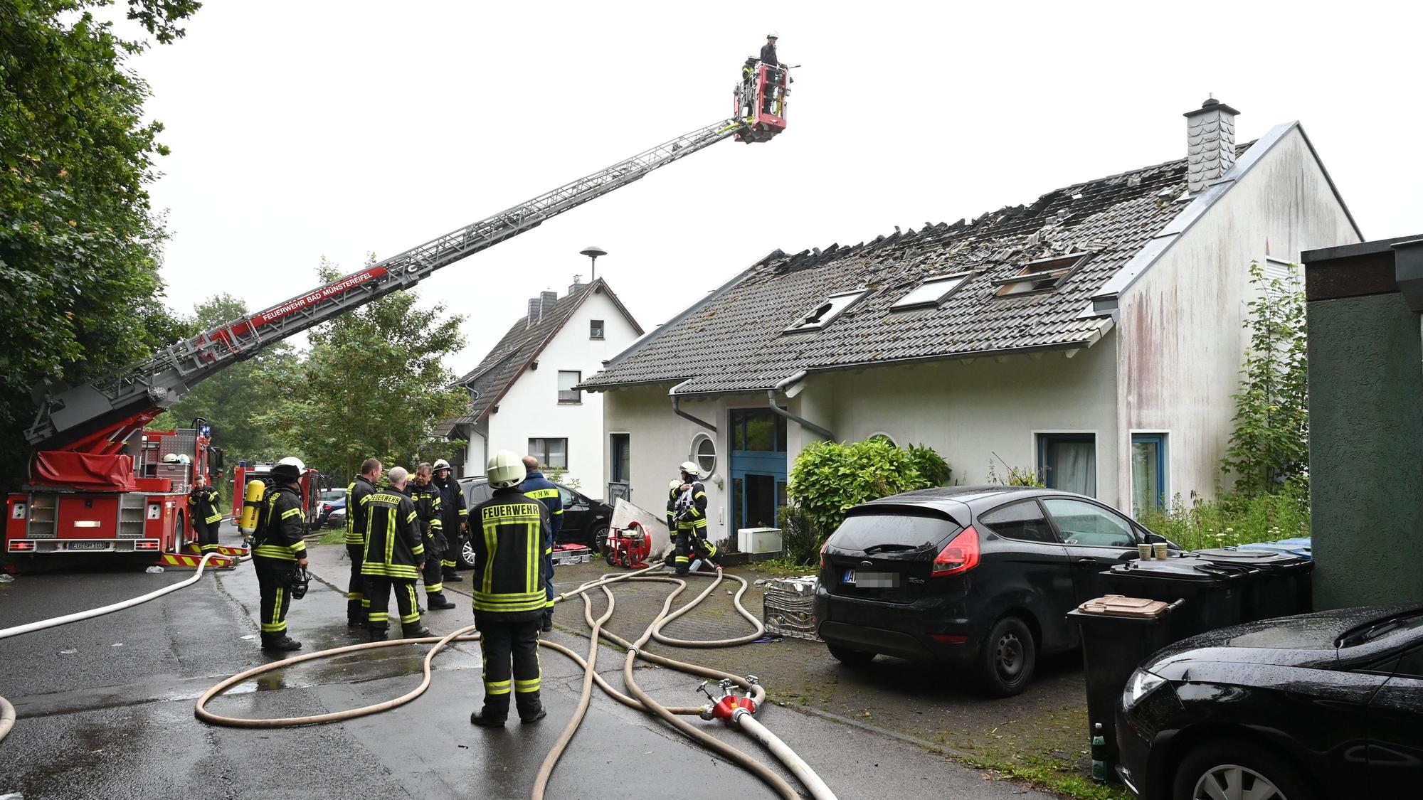 Die Feuerwehr hat über dem Haus eine Drehleiter ausgefahren, Einsatzkräfte stehen auf der Straße.