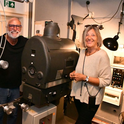 Die Vorsitzenden des Kinoklubs im Vorführraum des Berli-Kinos vor einem alten Projektor mit großer Filmspule.